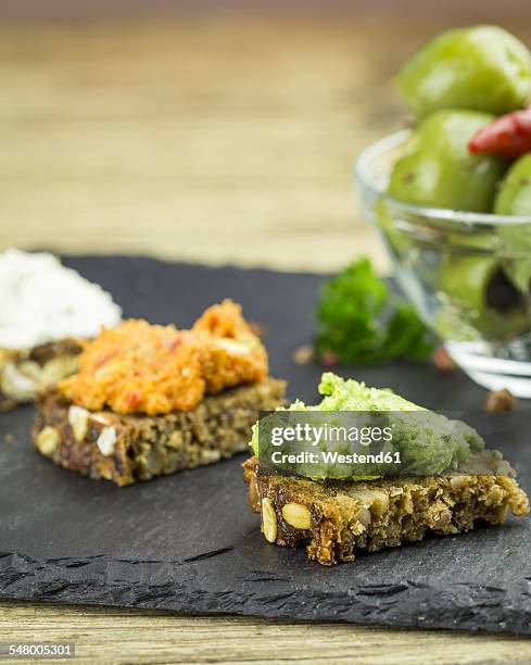 slices of wholemeal bread with different sheep cheese spread on slate - vollkornbrot stock-fotos und bilder
