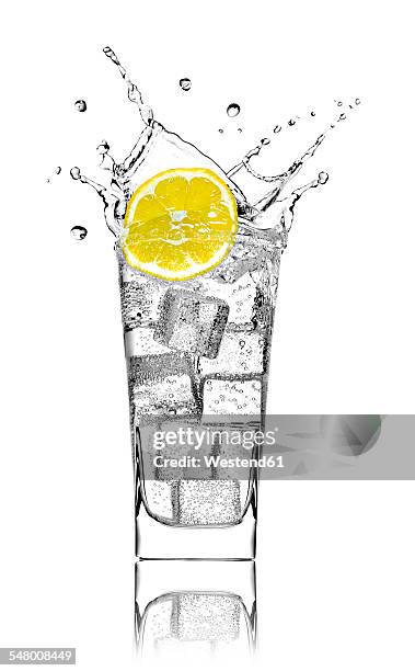 glass with soda water, ice cubes and slice of lemon in front of white background - sparkling water glass stock-fotos und bilder