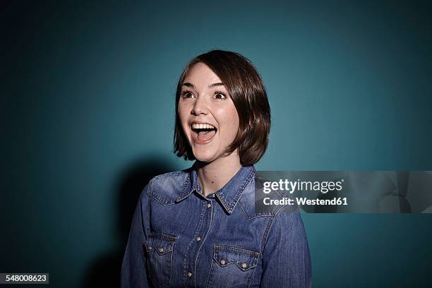 portrait of astonished young woman in front of blue background - funny situation woman imagens e fotografias de stock