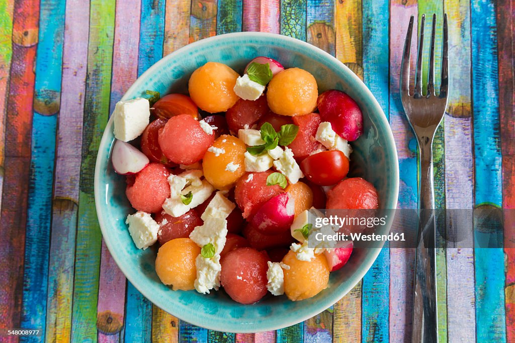 Melon salad with feta, tomato and red radish in bowl