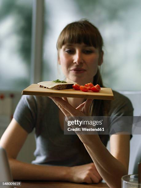 woman at desk holding board with snack - lunch cheese foto e immagini stock