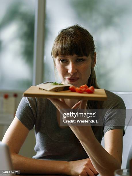 woman at desk holding board with snack - eating cheese stock-fotos und bilder