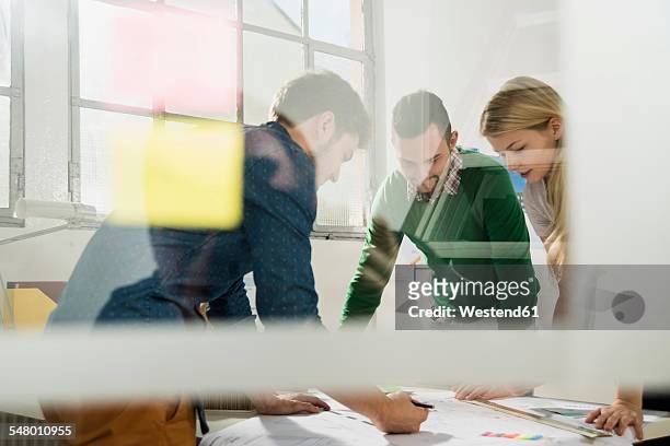 three young architects in office discussing - selective focus stock-fotos und bilder