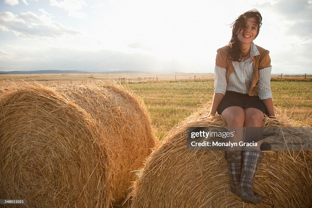 Smiling woman sitting on haystack