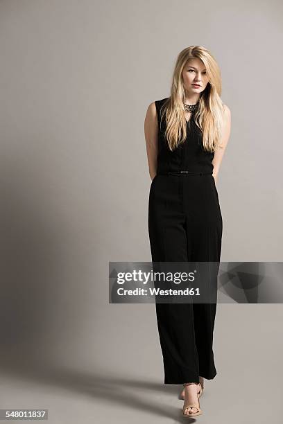 portrait of blond young woman wearing black overall - abendgarderobe stock-fotos und bilder