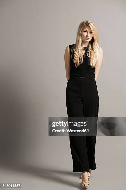 portrait of blond young woman wearing black overall - avondkledij stockfoto's en -beelden