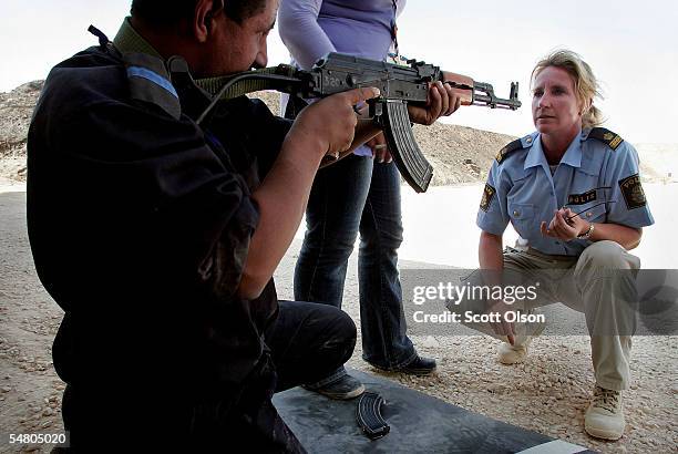 Camilla Jensen a police officer with the Swedish Police from Helsingborg, Sweden teaches an Iraqi Policeman how to shoot an AK-47 at the Jordan...
