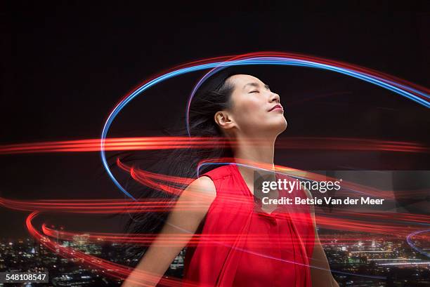 asian woman surrounded by lightbeams over city. - rastros de luz fotografías e imágenes de stock