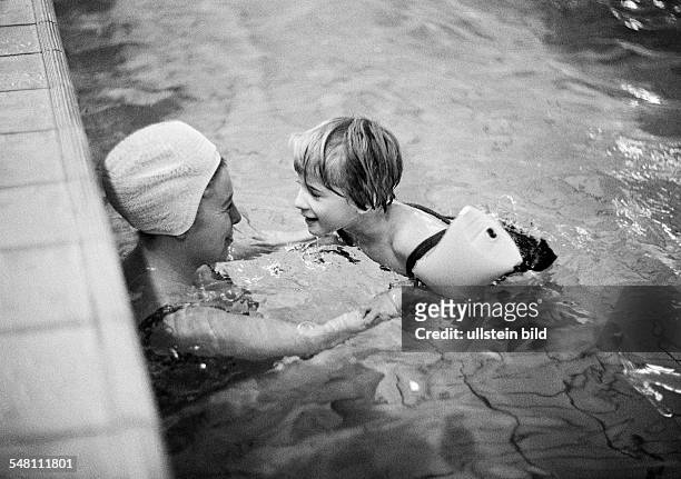 People, physical handicap, swimming lessons, teacher assists young girl in swimming exercises, arm floats, water wings, aged 30 to 40 years, aged 6...