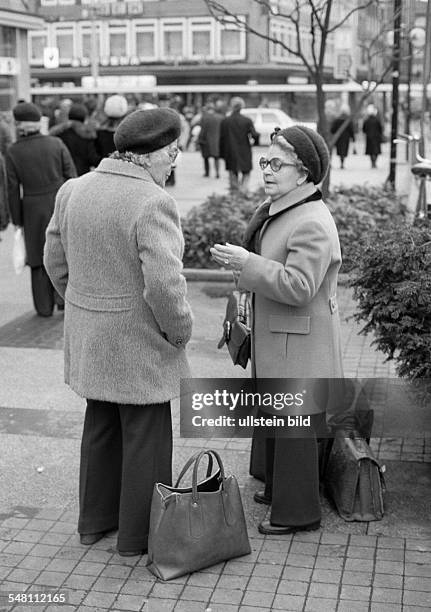 People, two older women in a conversation on the street, shopping bags, aged 70 to 80 years -