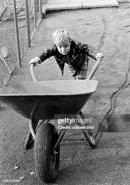 People, children, little boy moves a heavy wheel-barrow, exertion, aged 3 to 5 years -