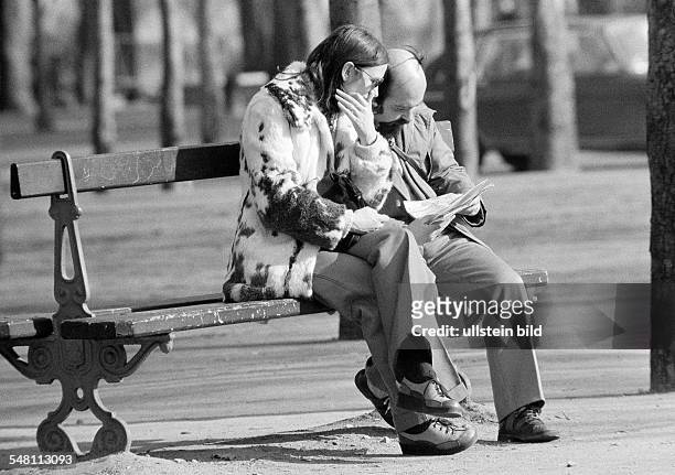 People, couple sits on a bench viewing a road map, aged 30 to 40 years, France, Paris -