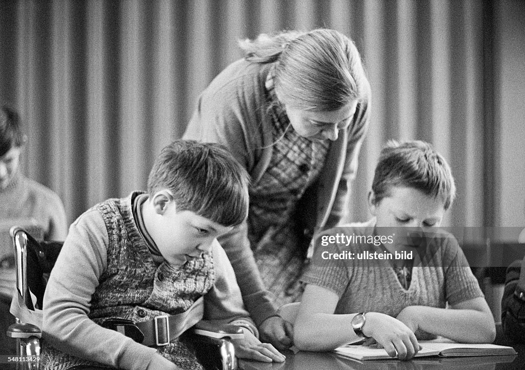 People, physical handicap, school lessons, teacher assists two boys in the exercises, reading, aged 30 to 40 years, aged 10 to 14 years, Maria, Special School Alsbachtal, D-Oberhausen, D-Oberhausen-Sterkrade, Ruhr area, North Rhine-Westphalia - 30.11