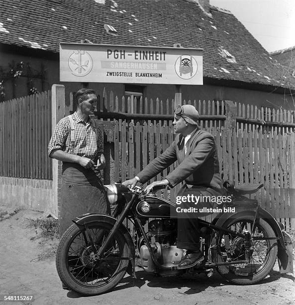 Motorradfahrer auf einem Motorrad vom Typ AWO 425 der VEB Simson, Suhl im Gespräch mit einem Arbeiter vor der PGH-Einheit Sangerhausen, Zweigstelle...