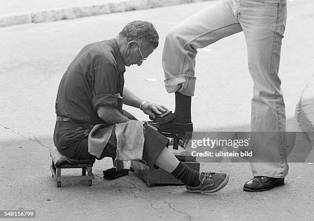 People, business, shoeblack sits on a taboret polishing shoes, aged 50 to 60 years, Spain, Valencia -