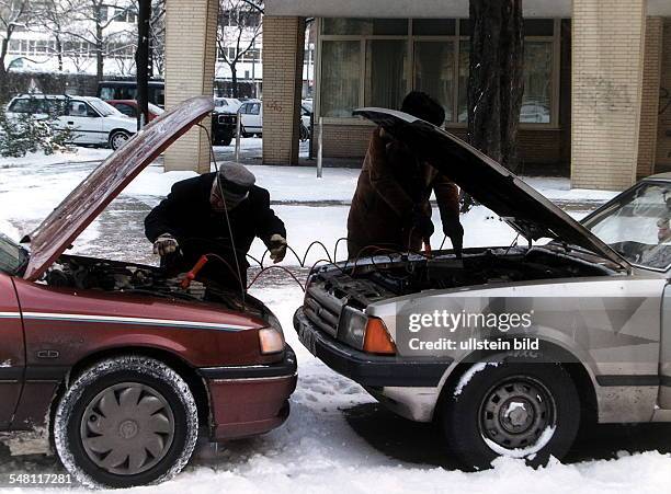 Ein Autofahrer gibt dem anderen Starthilfe: Aufladen der Batterie Dezember 1996