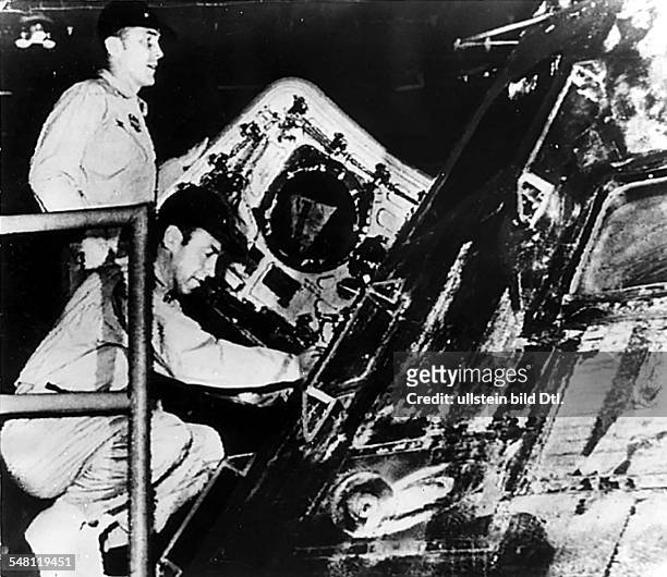 Nach der Bergung betrachten die Astronauten James Lovell und John Swigert an Bord der 'IWO Jima' die Kommandokapsel der Apollo 13, in der sie trotz...