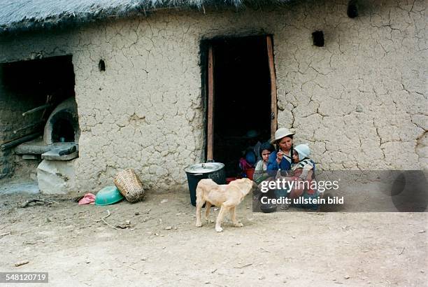 Chapaco - Indiofrau mit Kindern vor ihrem Haus. Ein Kind wird gefüttert. Ein Hund steht dabei. Links im Haus steht ein Backofen - 1995