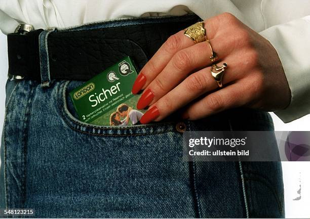 Symbolfoto 'Kondom nicht vergessen' - Hand einer Frau schiebt eine Packung Kondome in ihre Hosentasche - 1996