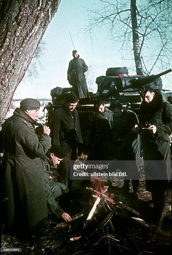 World War II German soldiers at the Eastern Front warming themselves at a fire; in the background a tank - November / December 1941 - Photographer: Artur Grimm -