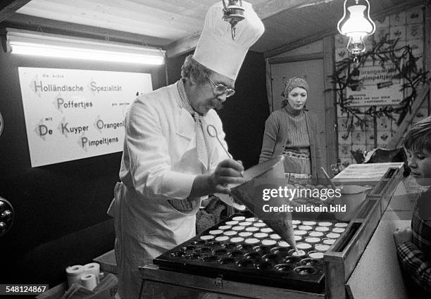 People, kermess, funfair, gourmet stall, cook with chefs hat prepares to bake sweet cookies and cakes, Poffertjes are a speciality from the...