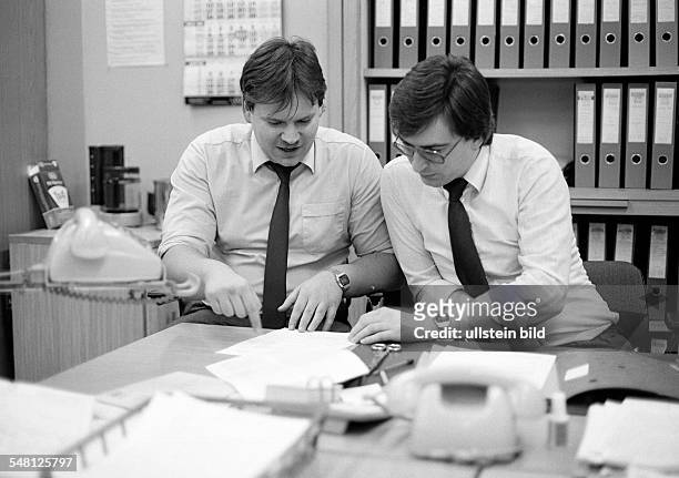 Economy, work, occupation, two office clerks at the writing desk in a talk, telephones, file cabinet, aged 25 to 35 years, Uwe, Wolfgang -