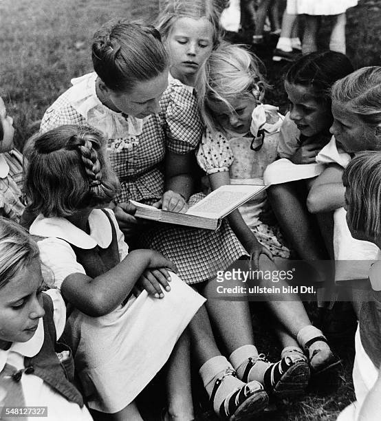 Germany : A student of the School of Arts and Crafts in Stuttgart reading to children of a kindergarten run by Nazi Germany's women's association -...