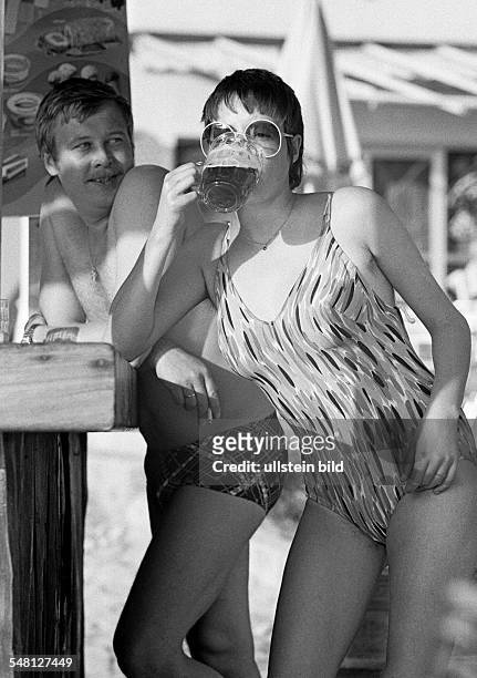 Holidays, tourism, young couple in bathing wear standing at a bar, girl drinks a beer, aged 25 to 30 years, Spain, Balearic Islands, Majorca,...