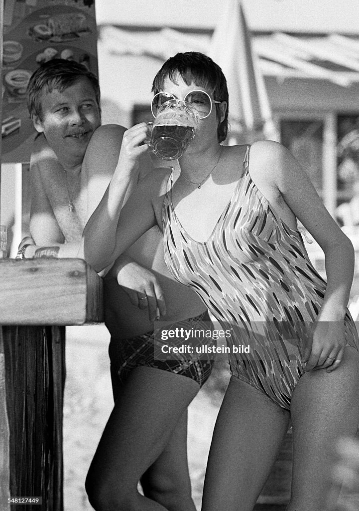 Holidays, tourism, young couple in bathing wear standing at a bar, girl drinks a beer, aged 25 to 30 years, Spain, Balearic Islands, Majorca, Guenter, Monika - 10.10.1978