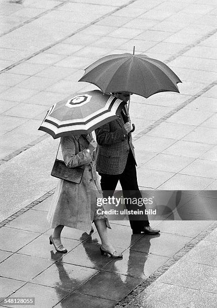 Couple undertakes a walk in the rain, umbrellas, aged 30 to 40 years -