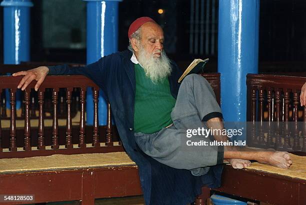 Jude sitzt auf einer Bank in der Synagoge "La Ghriba" auf der Insel Djerba und liest ein Buch - 1996