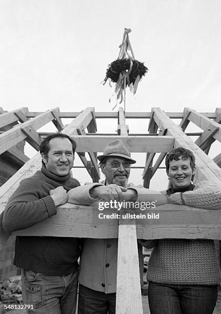 Building site, shell construction, one-family house, topping out ceremony, evergreen tree on the roof truss, building owners pose together with the...