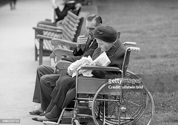 People, physical handicap, older woman sits in a wheel-chair, her husband sits beside her on a bench, aged 65 to 75 years, Great Britain, England,...