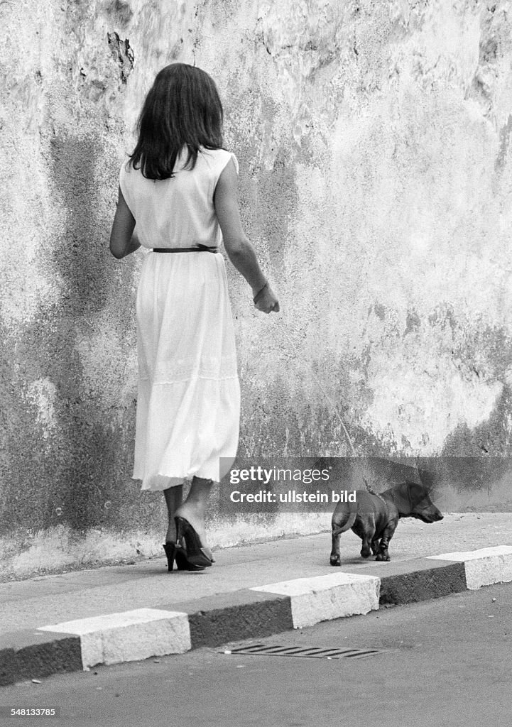 Human and animal, young woman walks a dachshund on a lead, aged 25 to 35 years, domestic dog, Canis lupus familiaris, Spain, Canary Islands, Canaries, Tenerife, Puerto de la Cruz - 15.04.1981