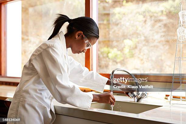 girl washing glass instrument en science class - eye guard stock-fotos und bilder