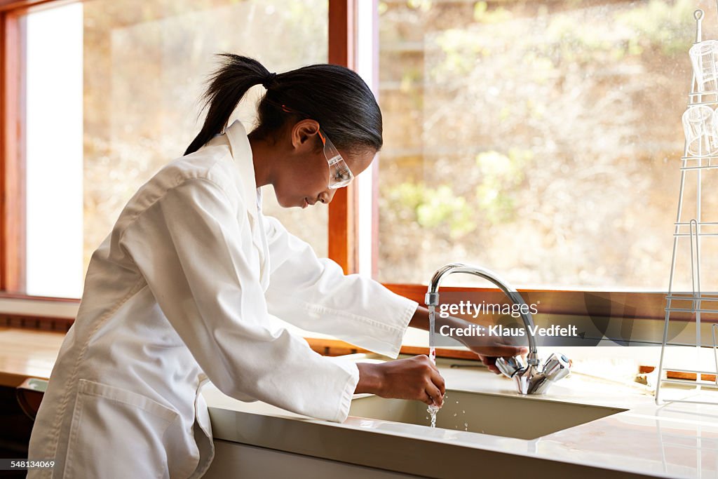Girl washing glass instrument en science class