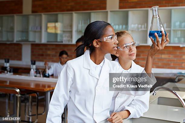two girls looking at beacon with blue liquid - chemische reaktion stock-fotos und bilder