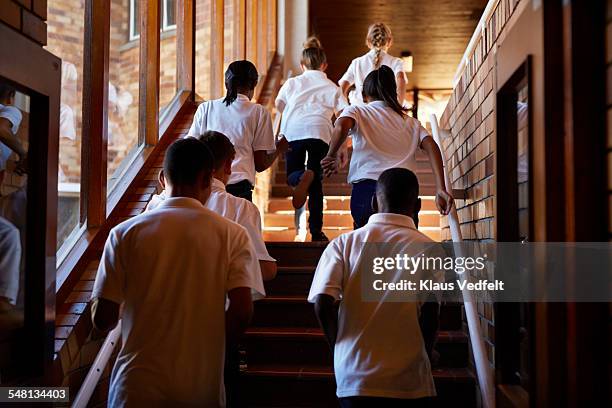 young students running up stairs at the school - schooluniform stockfoto's en -beelden