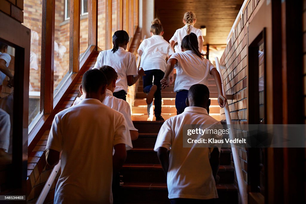 Young students running up stairs at the school