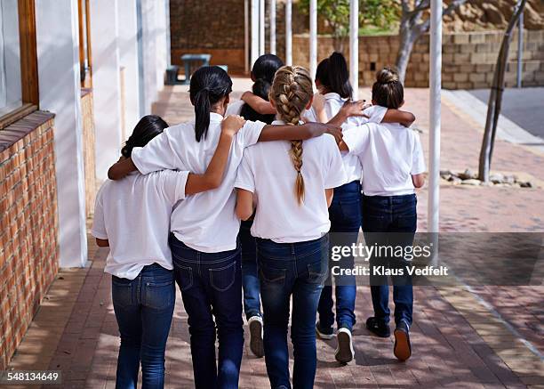 female students walking together in schoolyard - school uniform stock pictures, royalty-free photos & images