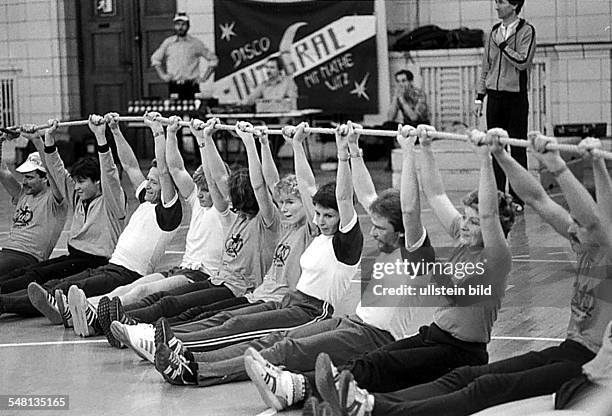 Jahrestag, Werbeveranstaltung Volkssport in der Sporthalle: - Gymnastik: Frauen und Männer halten ein Seil hoch