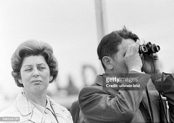 People, couple, freetime, contrasts, interest, boredom, man looks through a binoculars, woman is bored, aged 40 to 50 years -
