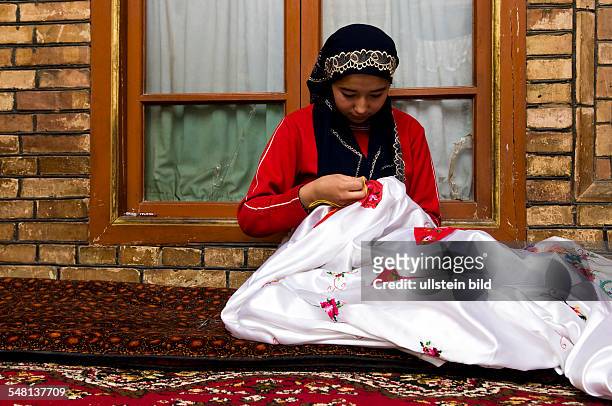 China Xinjiang Uyghur Kashgar or Kashi - young Uyghur woman is sewing