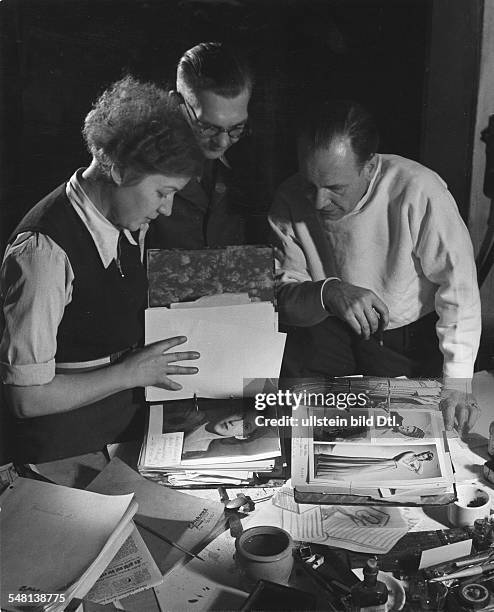 Photographer and assistant searching a catalogue for the right model for a photo shooting session - 1941 - Photographer: Regine Relang - Published...