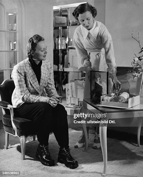 Model in a white jacket with green checks talking to the saleswoman in a perfumery - 1938 - Photographer: Regine Relang - Published by: 'Die Dame'...