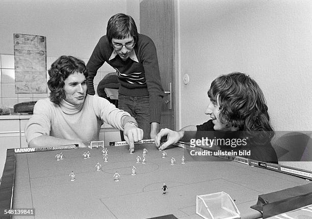 People, three young men playing table football, freetime, hobby, long-haired, aged 20 to 25 years, Juergen, Harald, Peter -
