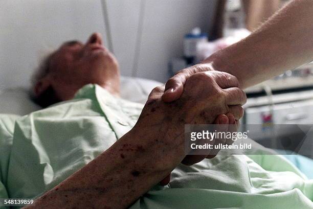 Abteilung für Geriatrie im Virchow-Klinikum Berlin: Krankenschwester hält die Hand einer sterbenskranken alten Frau - 1996
