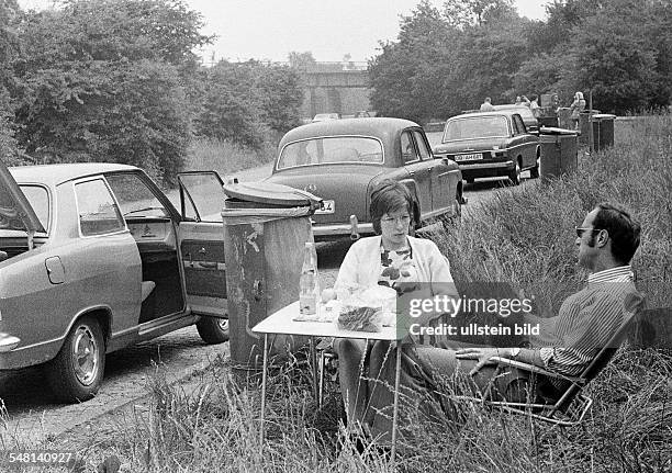 People, freetime, young couple takes a rest from motoring in a rest area, aged 25 to 35 years, picnic with folding chairs and a folding table, in the...