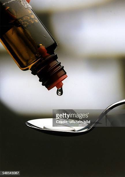 Flüssigkeit tropft aus einem Arzneifläschchen auf einen Löffel - 1994