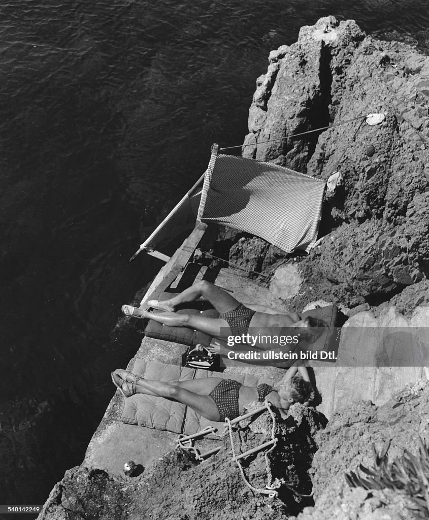 Couple wearing identical swimwear sunbathing on rocks at Cap Roux, Cote d'Azur (French Riviera) - 1939 - Photographer: Regine Relang - Published by: 'Die Dame' 12/1939 Vintage property of ullstein bild